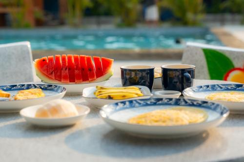 a table with plates of food and cups on it at Vang Vieng Moment Resort in Vang Vieng