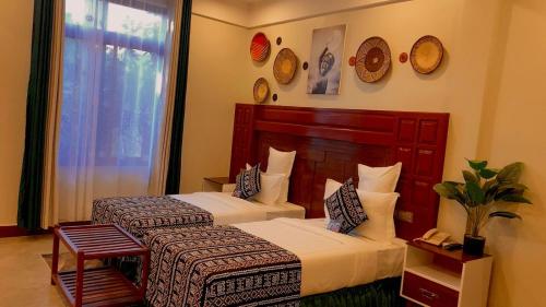 a hotel room with two beds and a window at Sunset Retreat Hotel in Arusha