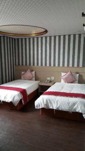 a hotel room with two beds with pink pillows at Mei Hua Hotel in Kaohsiung