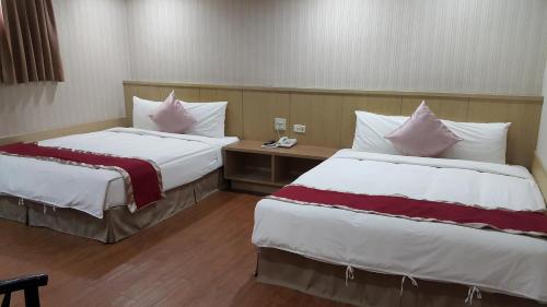 a hotel room with two beds with pillows at Mei Hua Hotel in Kaohsiung
