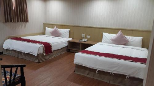 a hotel room with two beds with pillows at Mei Hua Hotel in Kaohsiung