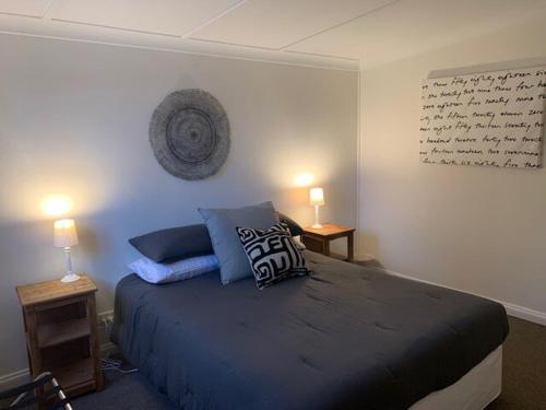 a bedroom with a bed with blue pillows on it at Peppertree Cottage in a beautiful Rural Setting in Mintaro