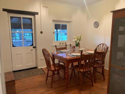 a dining room with a wooden table and chairs at Peppertree Cottage in a beautiful Rural Setting in Mintaro