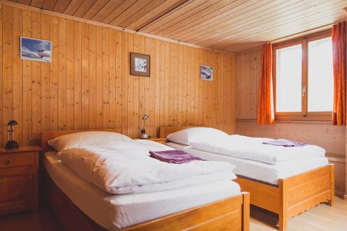 two beds in a room with wooden walls at The Lodge in Churwalden