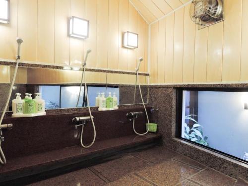 a bathroom with a sink and a shower with a mirror at Senso Yutagawa in Tsuruoka