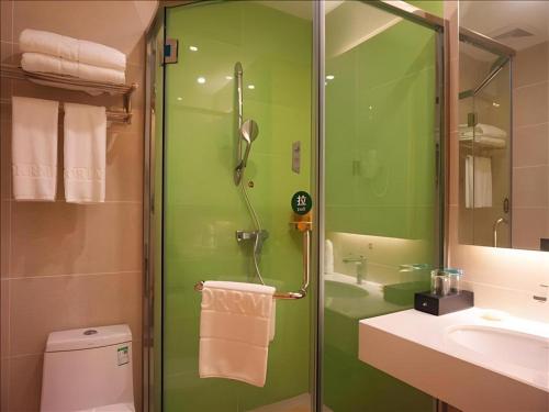 ein grünes Bad mit einer Dusche und einem Waschbecken in der Unterkunft Borrman Hotel Zhanjiang Shimao Building High-speed Railway Station in Tchia-k'am