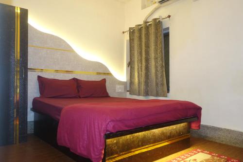 a bedroom with a bed with red sheets and a window at Hotel HCB (Hemo Chandra Bhawan) in Brahmapur