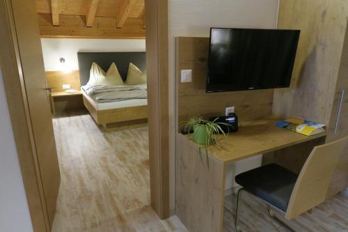 a room with a bed and a desk with a television at Apartment Madlaina in Samnaun
