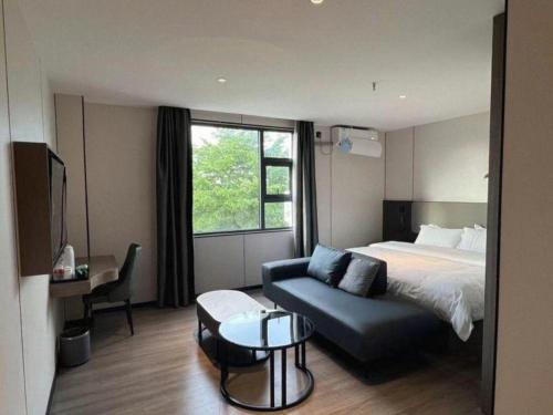 ein Hotelzimmer mit einem Bett und einer Couch in der Unterkunft GreenTree Inn Express Guangxi Nanning Mingyang Avenue Nanning Airport in Nanning