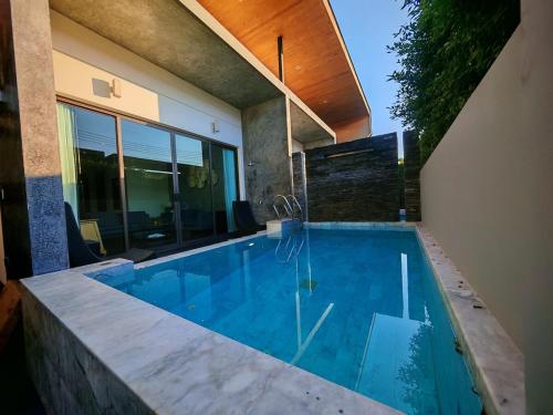 a swimming pool in front of a house at Chalong Modern 2 bedroom pool villa 2 minutes to fitness street and many tourist attractions in Ban Suan