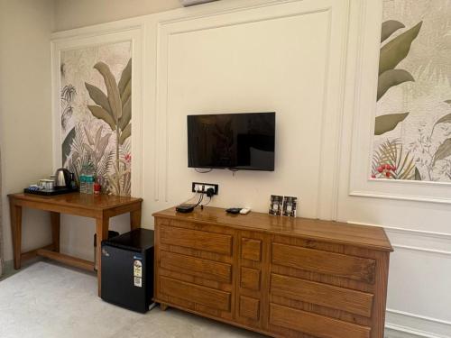 um quarto com um armário de madeira e uma televisão na parede em The Bhagwati Cottage & Villa em Ābu Road