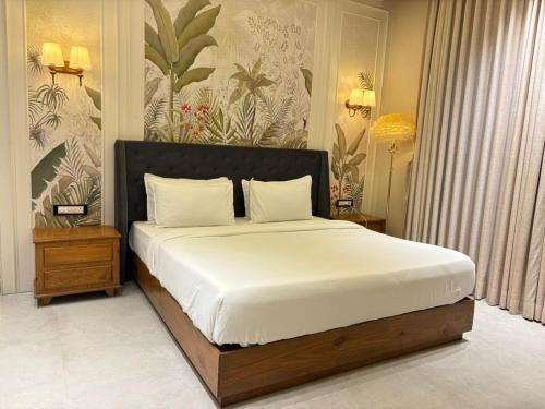 um quarto com uma cama grande com lençóis brancos em The Bhagwati Cottage & Villa em Ābu Road