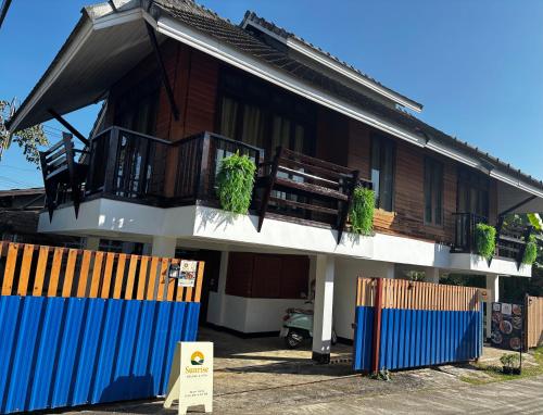 a house with a blue fence in front of it at Sunrise Brunch & Stay in Pai