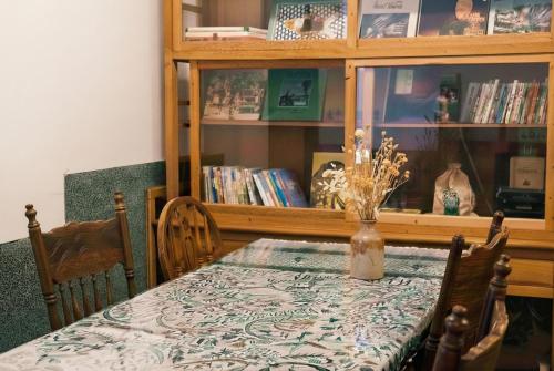 Una mesa de comedor con una estantería llena de libros. en FunNan Guesthouse, en Tainan