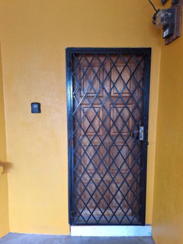 een deur met een metalen poort aan een gele muur bij Merak Roomstay in Paka