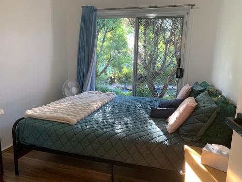 a bedroom with a bed with a large window at Fabulous Stunning Garden View King Bedroom with shared bathroom at MC 2079 in Mount Colah