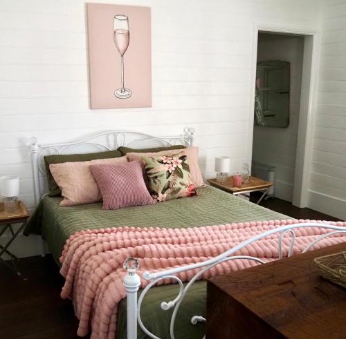 a bed with a green comforter and a wine glass at Smithtown Champagne Bed and Bubbles