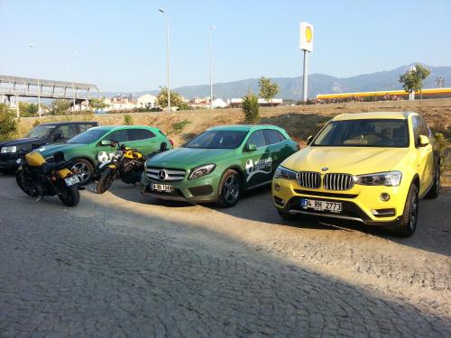 a group of three cars and a motorcycle parked on a road at Akcayhan Hotel in Akcay