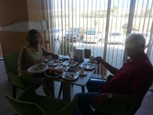a man and a woman sitting at a table with food at Akcayhan Hotel in Akcay