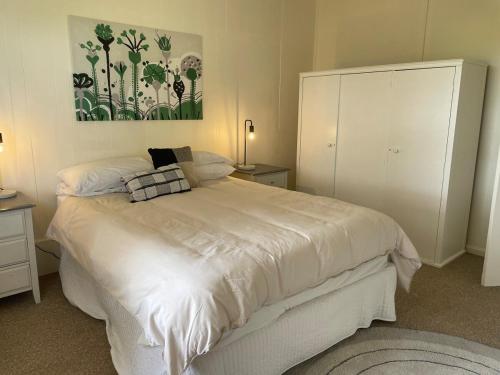 a bedroom with a white bed and a painting on the wall at The Vale Farmhouse Rural Setting in Farrell Flat