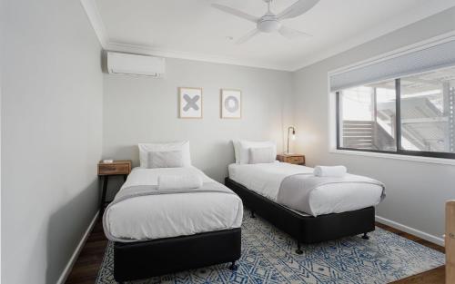two beds in a room with white walls and a window at The Nest in Bellingen