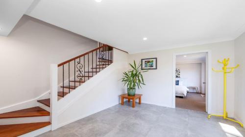a staircase in a white house with a potted plant at 'Treetops On The Bay - Water Views' by HolidayCo in Hardys Bay