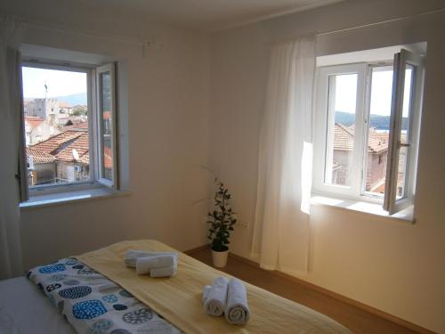 a bedroom with two windows and a bed with towels at Apartments An Ni in Korčula