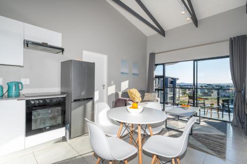 a kitchen and dining room with a table and chairs at Lagoon Views Luxury Apartment Langebaan in Langebaan