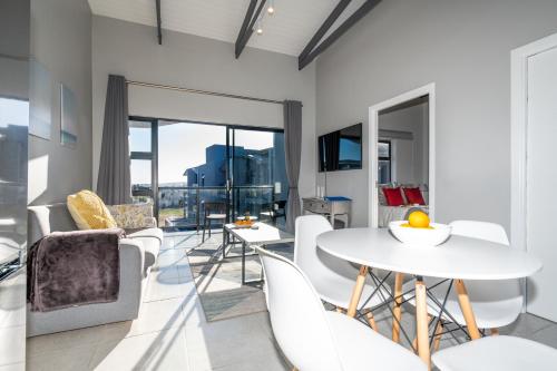 a dining room with white chairs and a table at Lagoon Views Luxury Apartment Langebaan in Langebaan