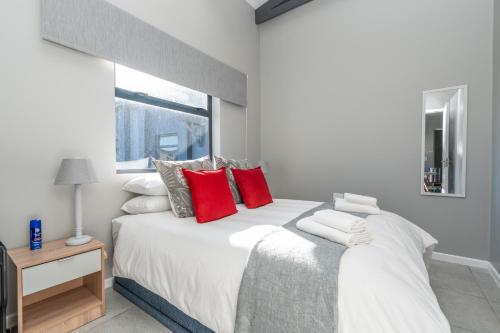 a bedroom with a large white bed with red pillows at Lagoon Views Luxury Apartment Langebaan in Langebaan