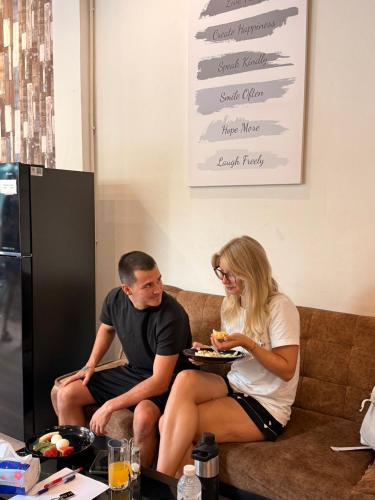 een man en een vrouw zitten op een bank en eten eten bij Aura Hostel in Bangkok