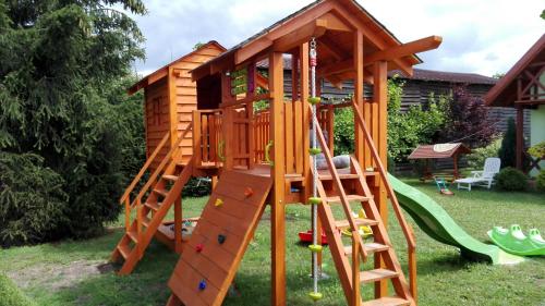 a wooden play house with a slide at Zielony Domek Kruklanki in Kruklanki