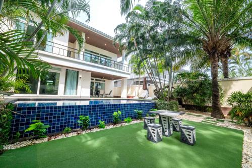 a house with a green lawn in front of a swimming pool at Pattaya Private 4-Bedrooms, 5-Bathrooms Pool Villa in Jomtien Beach