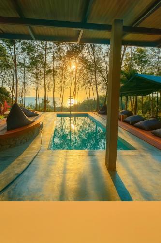 a swimming pool with the sunset in the background at Drifters Anchor in Ban Map Khangkhao