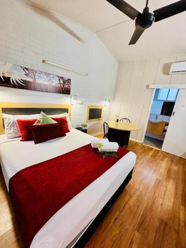 a bedroom with a large bed with a red blanket at Downs Motel in Toowoomba