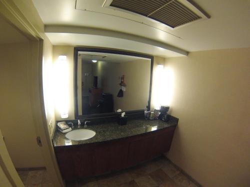 a bathroom with a sink and a large mirror at The Biltmore Hotel & Suites Main Avenue in Fargo