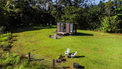 a small cabin in the middle of a field at White Jacaranda Tiny House by Tiny Away in Maleny