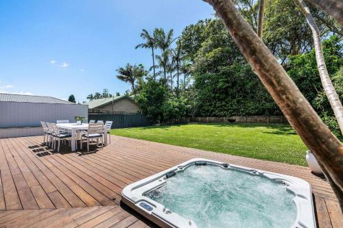 a hot tub on a deck with a table and chairs at Forresters Lodge by Coast Hosting in Wamberal North