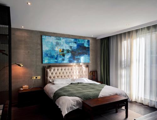 a bedroom with a bed and a painting on the wall at Suzhou Unique Space Design Art Hotel in Suzhou