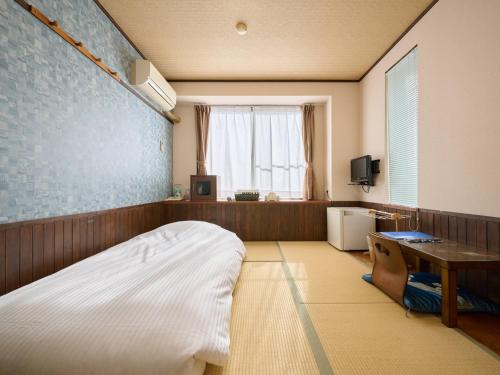 a room with a bed and a desk and a window at Business Hotel Wayoukan in Inazawa