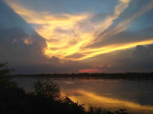 a sunset over a body of water with clouds at Mut Mee Garden Guest House in Nong Khai