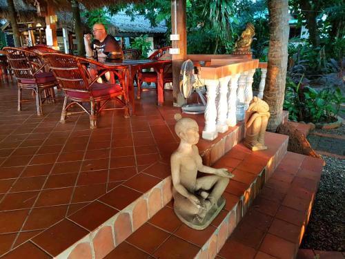 a statue of a boy sitting on a brick wall at Mut Mee Garden Guest House in Nong Khai