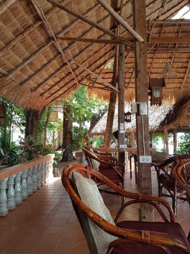 a group of chairs and tables under a straw roof at Mut Mee Garden Guest House in Nong Khai
