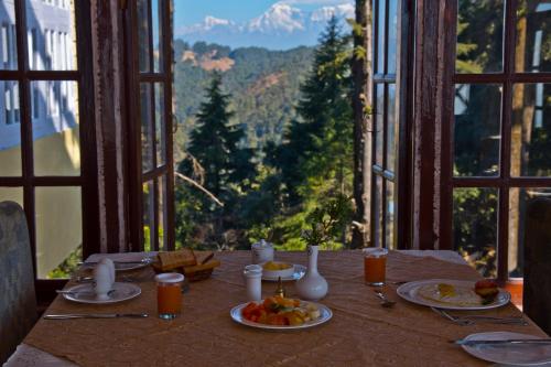 uma mesa com comida e vista para uma montanha em Tree of Life Grand Oak Manor Binsar em Binsar