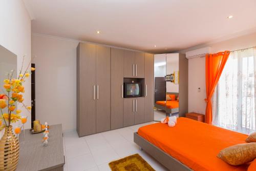 1 dormitorio con 1 cama de color naranja y TV en Marsascala 2 Bedroom Apartment close to Beach! HPI 6768, en Marsaskala