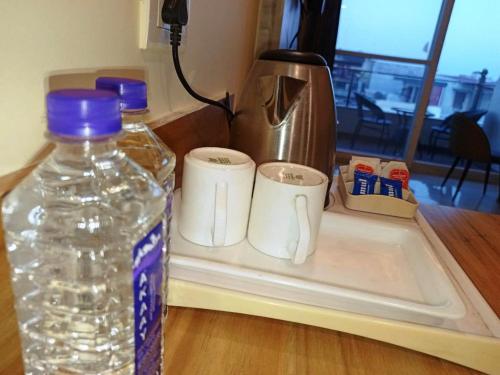 a bottle of water and two cups on a counter at MLS Prime Inn - Near Dehradun Railway Station in Dehradun