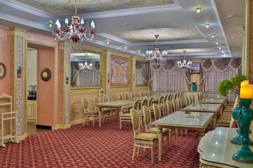 a dining room with tables and chairs and chandeliers at Amsterdam Hotel Aktobe in Aktobe