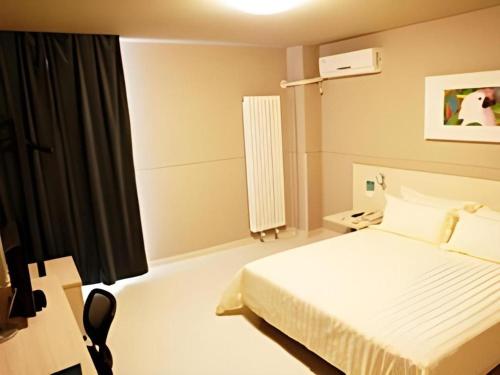 um quarto com uma cama branca e uma janela em Jinjiang Inn Yantai Penglaige Zhonglou North Road em Penglai