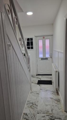 a hallway with a white door and a tile floor at Nice Living Serviced Accommodations Birmingham 2 in Birmingham