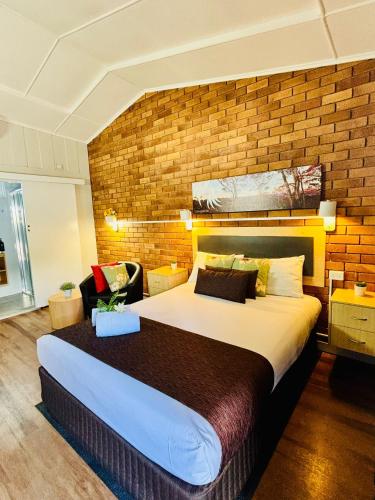 a bedroom with a large bed and a brick wall at Downs Motel in Toowoomba
